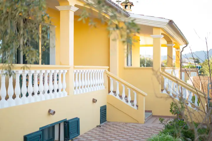 Casa gialla con veranda e balaustra bianca